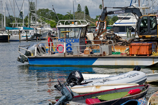 A workboat labeled DIVE COM and several small dinghies tied at a marina dock. Editorial Use Only, September 16,  2026 ,Gulfport, FL ,USA, surrounded by marine equipment, outboard motors, scrap materia
