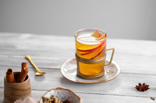 Hot autumn apple cider with fresh apple slices, spiced drink on rustic table