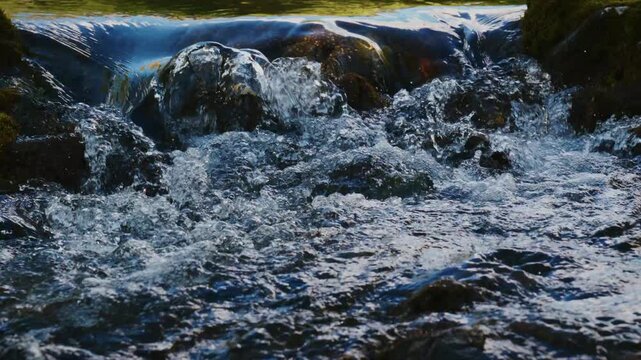 Rapid river flows over mossy rocks. Water crashes and splashes with force. Shadows and highlights define the scene. Perfect for nature, adventure, or environmental themes