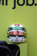 Obraz premium NEW YORK, USA – SEPTEMBER 16, 2026: a Formula 1 racing helmet on a green display background with sponsor logos and reflective visor.