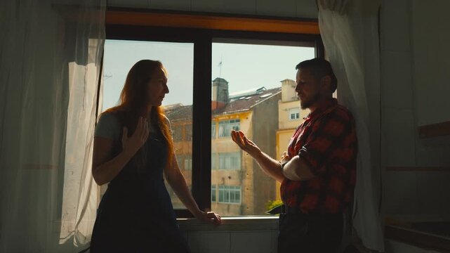 Couple having difficult conversation in kitchen by window