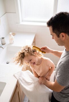 Loving Father Combing His Little Daughter's Curly Hair in the Bathroom During Morning Routine