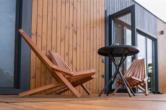  relaxing outdoor terrace with wooden folding lounge chairs and a compact coffee table, offering a comfortable space to unwind and enjoy the surroundings.  wellness, slow living, and minimalist lifest