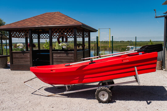 A red boat for fishing and outdoor recreation&mdash;complete with a trailer for transport to lakes or rivers&mdash;and a gazebo for relaxing. Summer outdoor recreation.