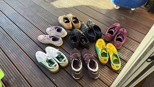 den haag, netherlands - January 14 2026: Different pairs of shoes are placed on a wooden deck in Den Haag. They show various styles and colors.