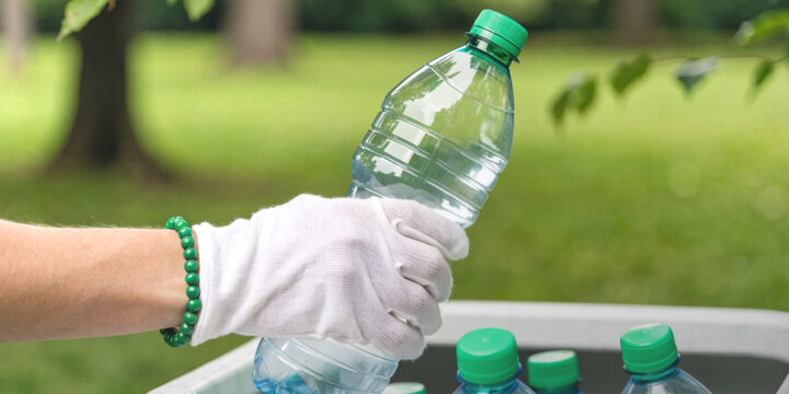 Recycling and protecting the environment with hands wearing white gloves are collecting plastic bottles and sorting them into bins