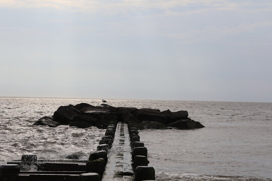An old wood and stone jetty sitting in the calm wake of the North Cape May Bay on a summer evening.