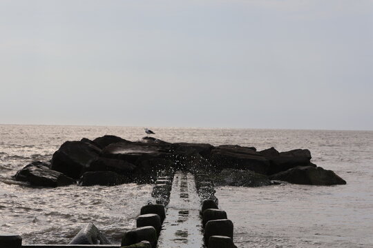 An old wood and stone jetty sitting in the calm wake of the North Cape May Bay on a summer evening.