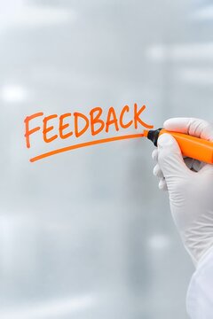 Medical professional using orange marker to write feedback on transparent surface in clinical setting