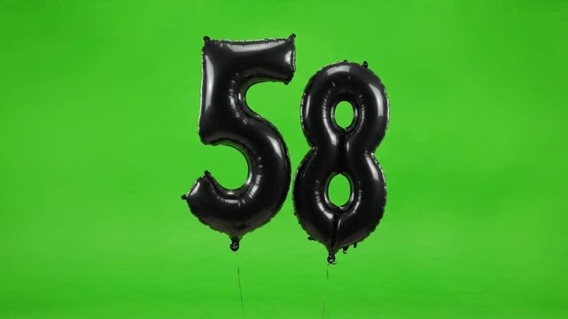 Black foil number fifty-eight balloon floating up on green screen background