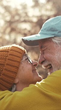 Adorable elderly couple hugging with love and affection, smiling and having fun outdoors with a blurred nature background. Romantic portrait of two senior people enjoying retirement together