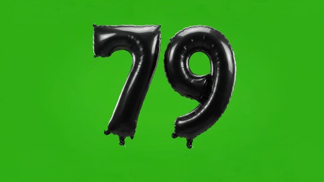 Black foil number seventy-nine balloon floating up on green screen background