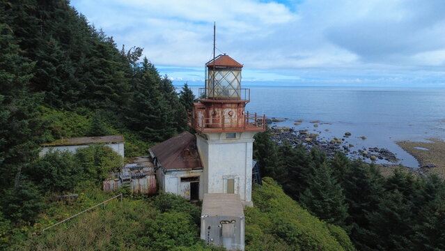 Behind a lighthouse on a cliff, looking out to sea.
