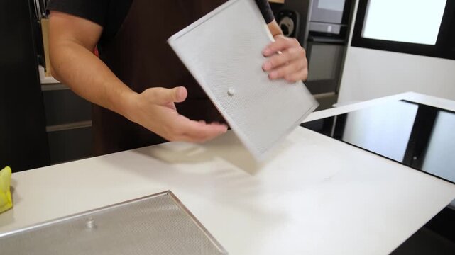 Professional handyman installing a new clean filter on a modern downdraft extractor hood