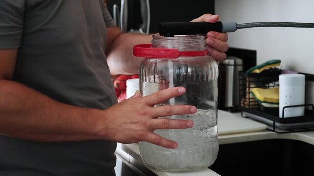 Unrecognizable person adding fresh water in a jar for a fish tank water change at home