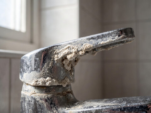 Dirty faucet covered with heavy limescale and calcium deposits in bathroom