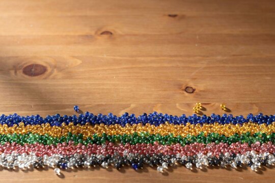 Bands of coloured glass beads sorted across a warm pine tabletop