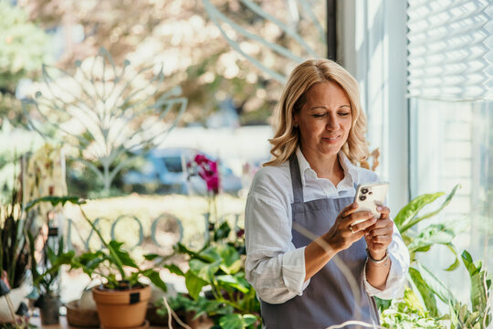 Female florist using smartphone managing small business online