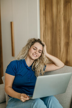 Woman relaxing on couch working with laptop at home