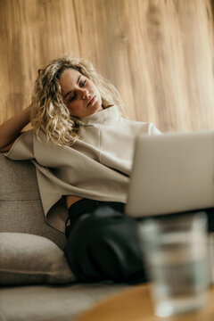 Woman working remotely on laptop at home sofa