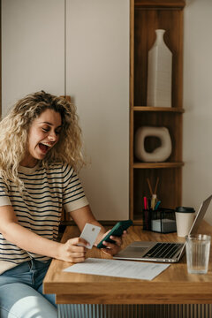 Happy woman enjoying online shopping with credit card and smartphone