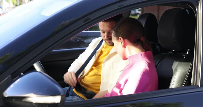 Driving school. Instructor and student fastening seat belts in car