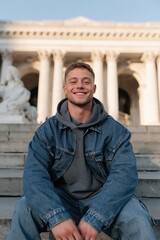 Fototapeta premium Young man smiling on grand city steps background for lifestyle banner and website background design