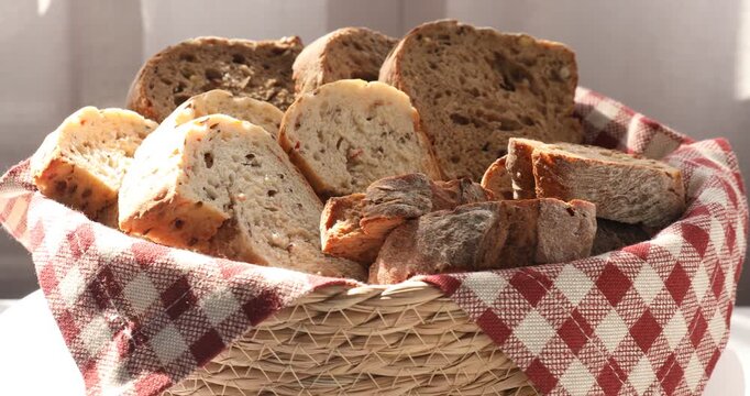 Different types of bread in wicker basket on table indoors, closeup