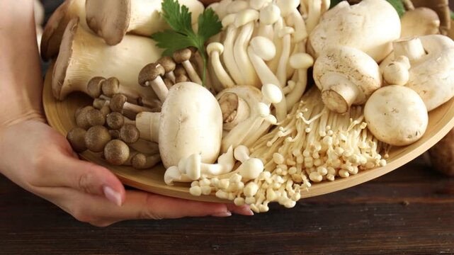 Woman taking different mushrooms at wooden table, closeup