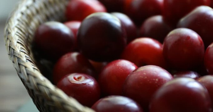 Ripe red cherry plums in basket, spinning. Closeup view