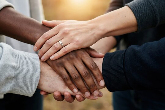 Diverse group of people stacking their hands together in a show of unity and support