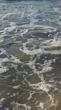 Close-up de espuma e ondas do mar quebrando na areia, textura din&acirc;mica da natureza durante viagem ao litoral