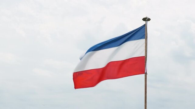 Dutch red white and blue upside down flag protest sign against a cloudy sky. Farmers in the Netherlands protesting against forced shrinking of livestock because of CO2 emissions.	