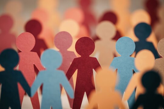 Group of colorful paper cutout people holding hands