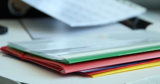 Businesswoman placing punched pocket with documents into file folder at table, closeup. Selective focus