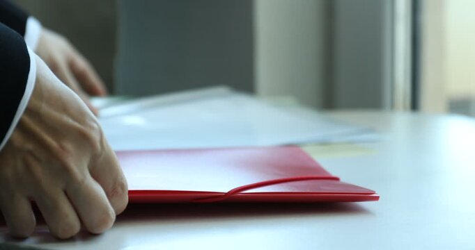 Businesswoman stacking file folders at table, closeup