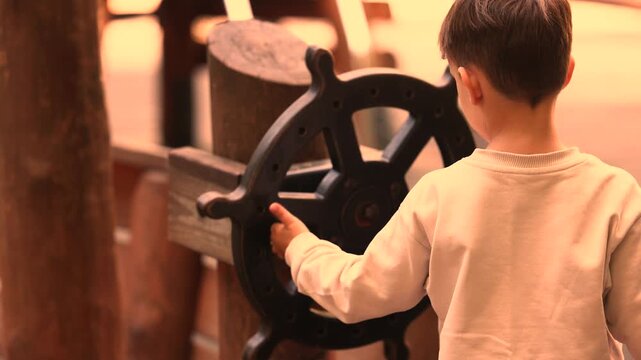 Golden hour light bathes boy steering pirate ship wheel outdoors