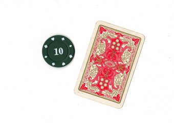 A vintage playing card and poker chip isolated on a white background. © Philip