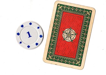 A vintage playing card and poker chip isolated on a white background. © Philip