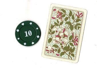 A vintage playing card and poker chip isolated on a white background. © Philip