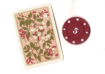 A vintage playing card and poker chip isolated on a white background. © Philip