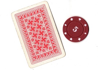 A vintage playing card and poker chip isolated on a white background. © Philip
