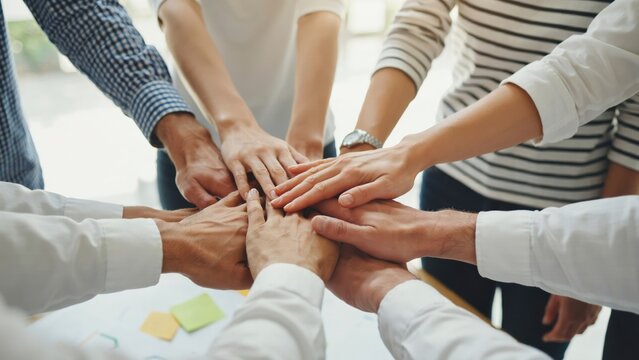 Group of business people stacking hands together for teamwork and unity