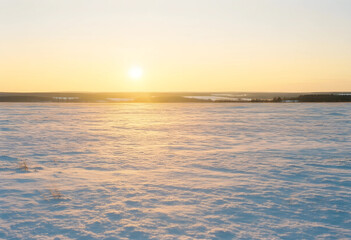 Fototapeta premium Winter landscape at sunrise, serenity and peace with golden light over a vast snow covered field in a cold rural environment during early morning