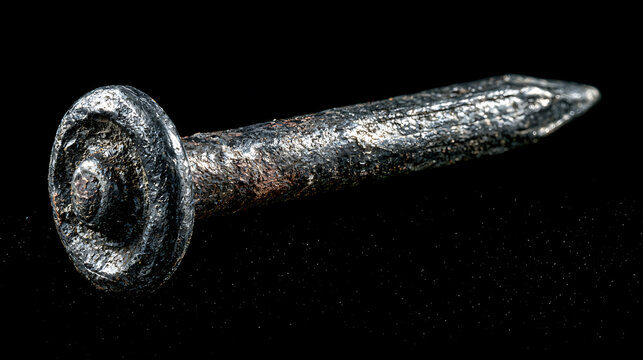 A weathered metal nail isolated on a black background detailed closeup