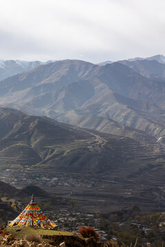Prayer flag draped stupa overlooking a terraced valley, Tongren County, Longwu, China