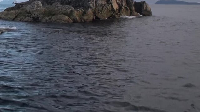 A low rocky island rises from dark cold water. The wider composition also shows wide framing, with natural light, surface texture and spatial depth remaining visible.