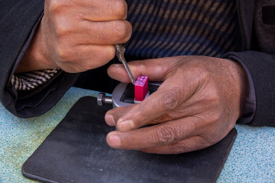 Craftsman's hands carve a traditional Chinese stamp on a workbench, Gansu Province, Linxia, China