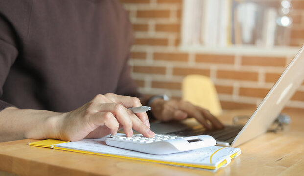 close up man hand press on calculator and check invoice letter from bank to check about debt and spending monthly for people lifestyle and inflation economic concept
