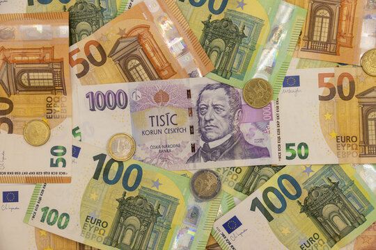 Czech koruna and euro banknotes arranged together as physical paper currencies, displaying the distinctive colors, denominations, portraits, architectural motifs, national symbols